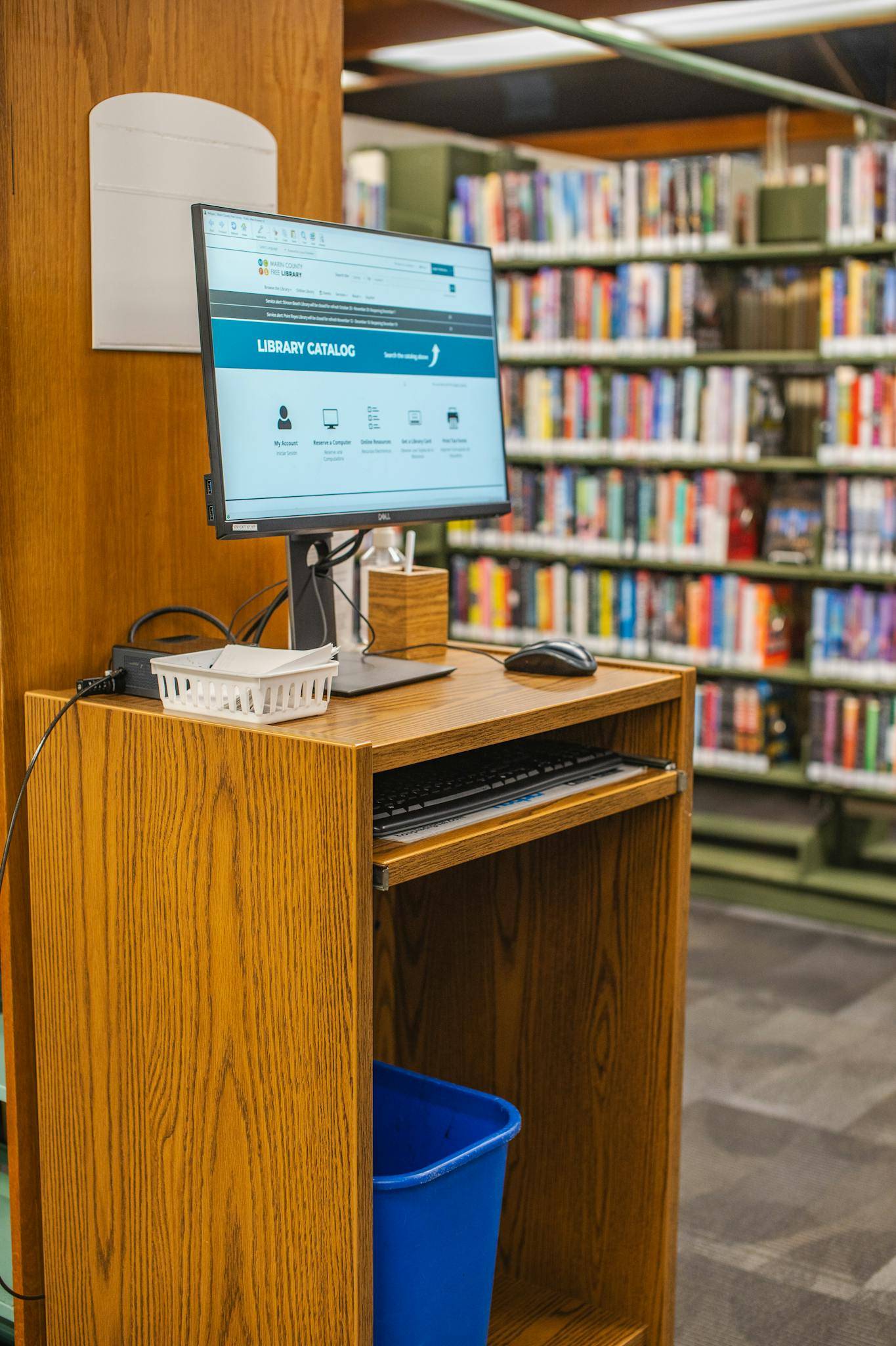 Library computer station showing a catalog screen with bookshelves in the background.